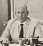 man sits at a desk looking at the camera