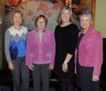 four women stand together smiling at the camera