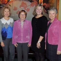 four women stand together smiling at the camera
