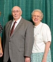Dr. Richard and Patricia Petre stand next to each other in front of a green backdrop