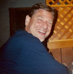 man looks over his shoulder smiling at the camera