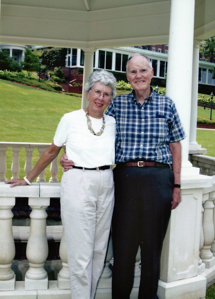man and woman stand with their arms around each other smiling