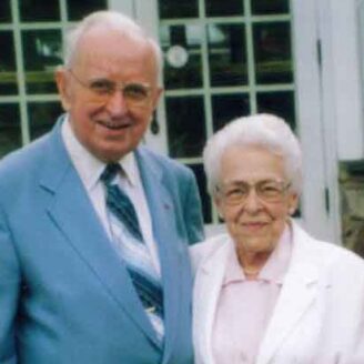 A senior couple pose and smile for the camera.