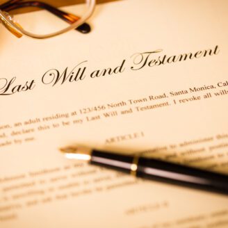 A document titled "Last Will and Testament" sits on a table with reading glasses and a pen.