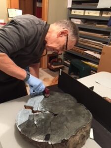 An artist leans over a piece of wood as he carves.