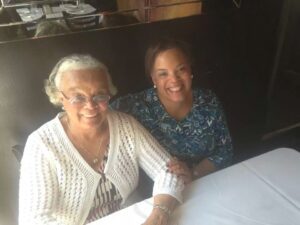 Two women sitting at a table smile for the camera.