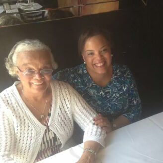 Two women sitting at a table smile for the camera.