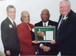 Four individuals stand holding a plaque and posing for a photo.