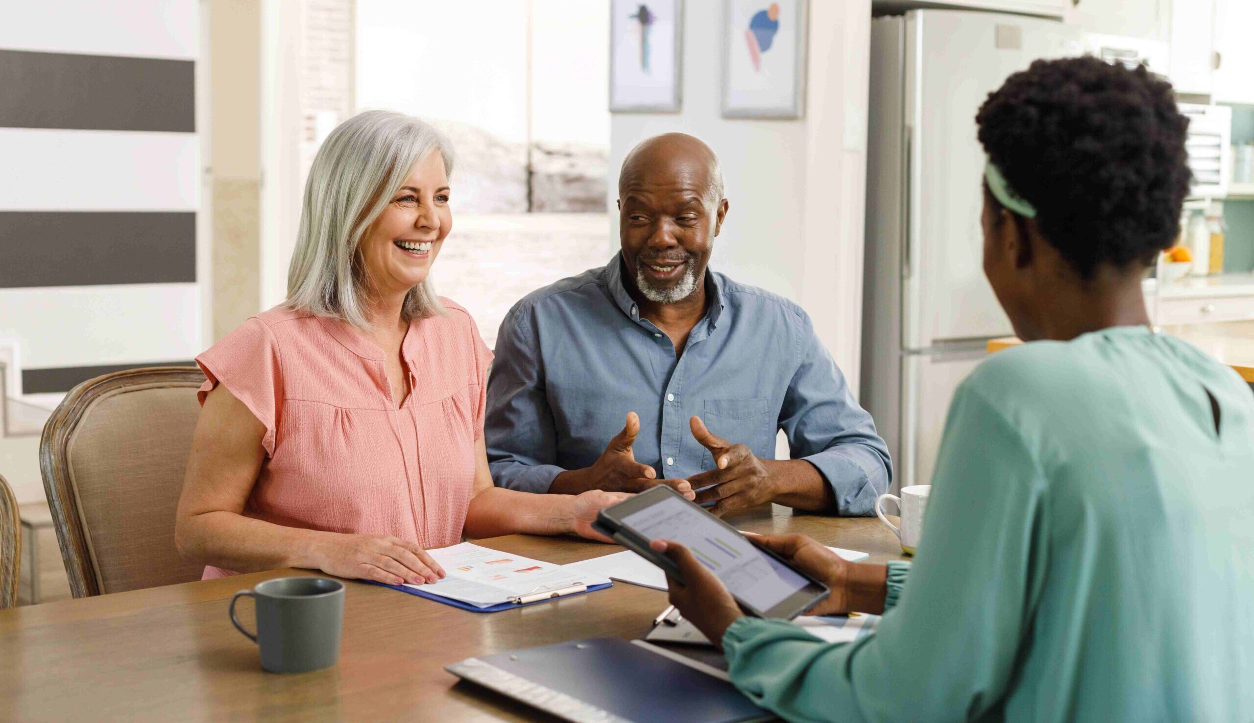 A couple speaks to a person holding an ipad and financial documents. 