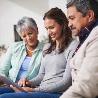 two older adults look at a tablet held by a younger adult