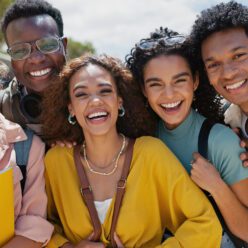 a diverse group of young graduates smile and lean in towards the camera