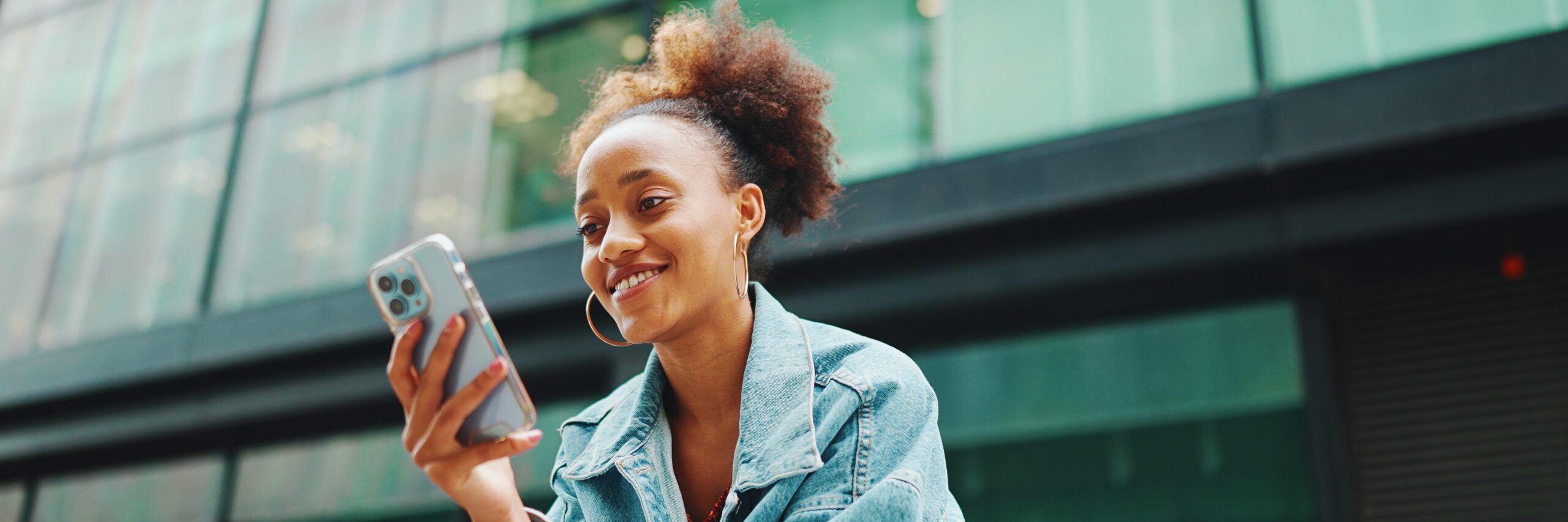 young woman looks at her mobile phone smiling
