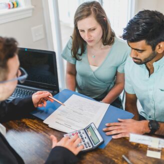 Couple sits across from a a man looking over documents