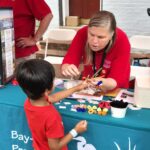 Amy Rembold helping a child make a butterfly ring craft