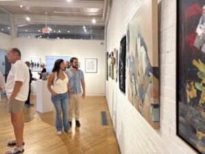 Man and woman walk in an art gallery looking at art on the walls