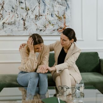Two people sitting, comforting one another.