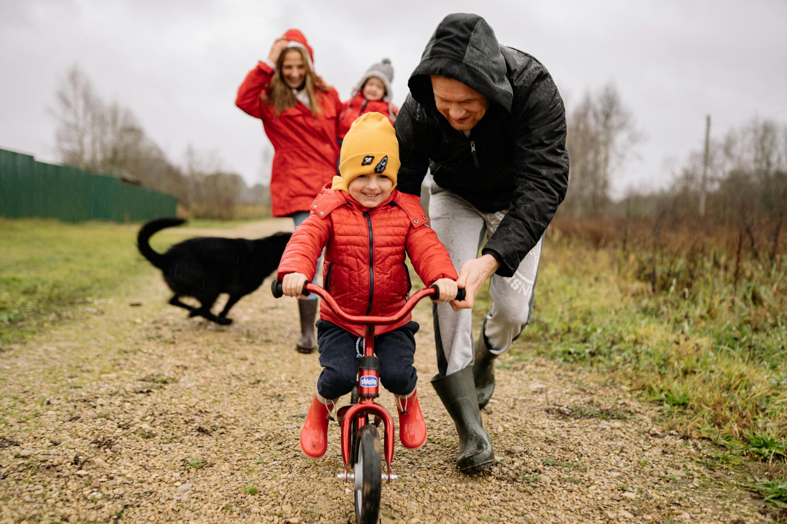Child biking with parents helping.