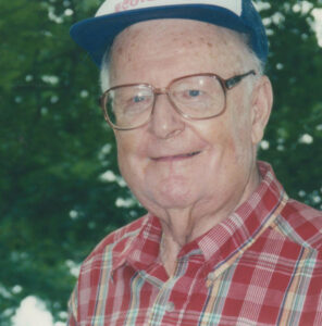 man wearing a baseball cap and flannel shirt looks smiling at the camera