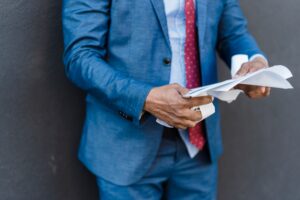 man is suit holding paper
