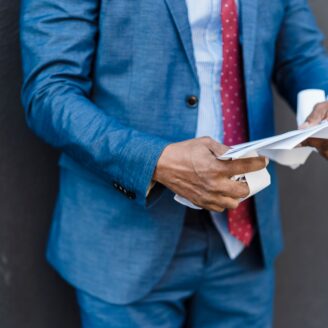man is suit holding paper
