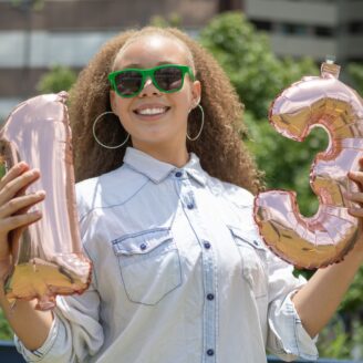 woman holding balloons that say "13"